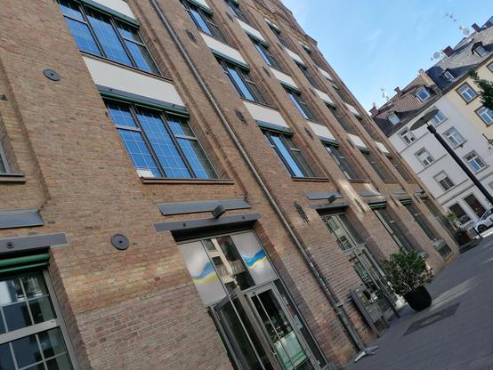Ein modernisiertes altes Fabrikgebäude aus Backsteinen mit großen Fenstern und Glastüren.