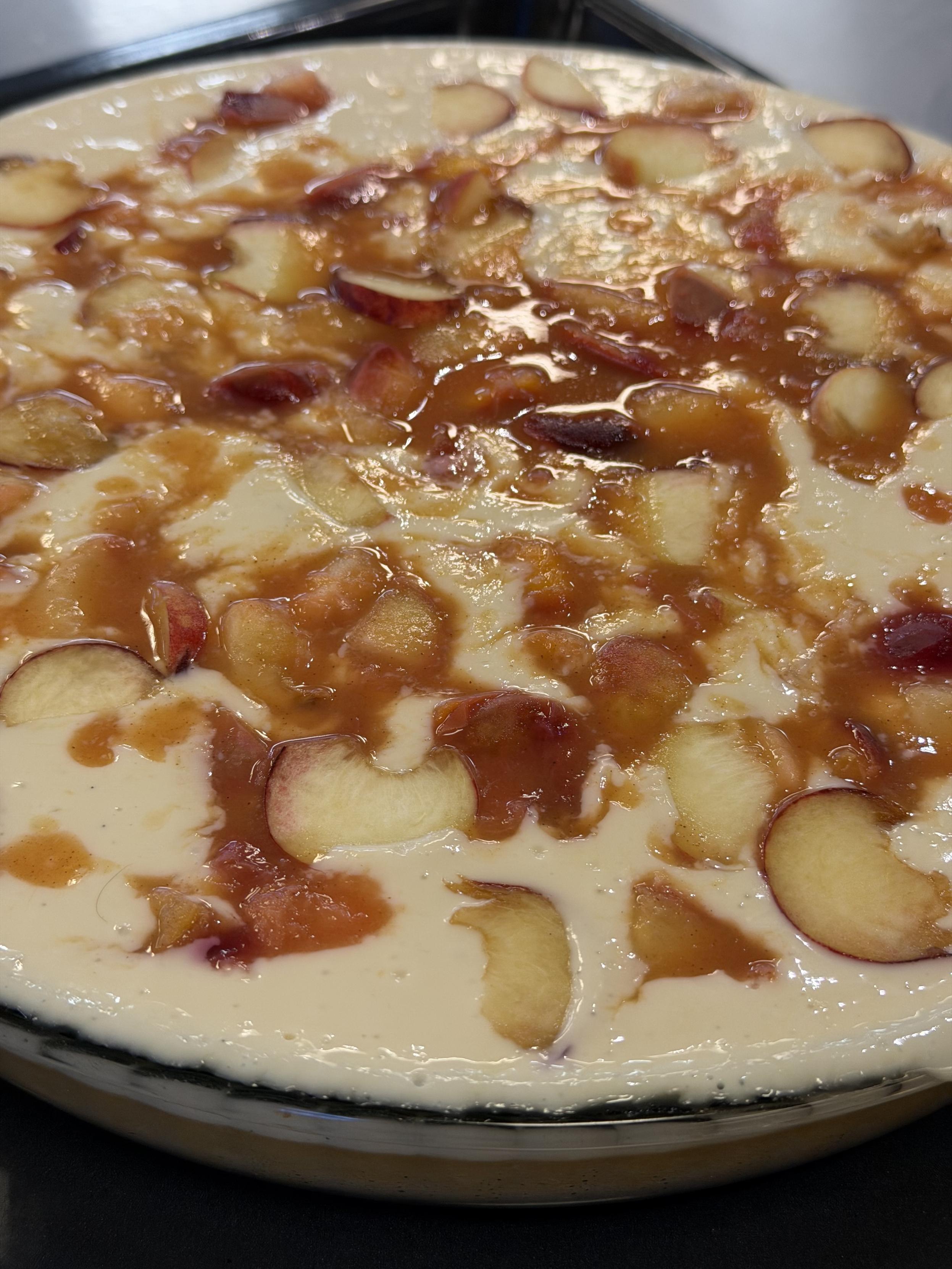 Nahaufnahme eines veganen Tiramisus in einer Glasschale, bedeckt mit heller Creme, fruchtigem Kompott und Mandelblättchen.